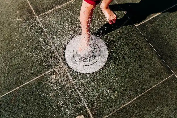 赤脚小男孩在温泉里的游泳池流过喷口水