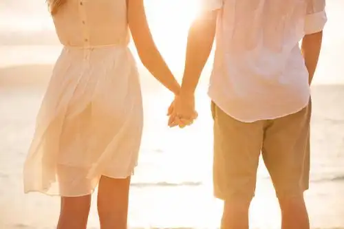 海滩日落下的情侣手牵手