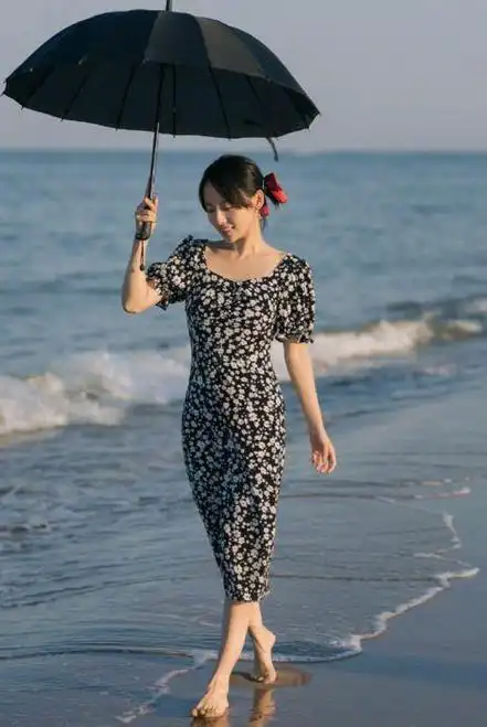 就张嘉倪的这个造型来看,她穿着一条黑色碎花裙,光着脚丫走在沙滩上