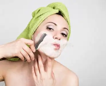 护肤行业漂亮的年轻女人穿着浴巾,用直剃刀刮胡子.