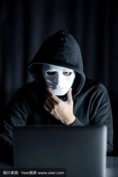神秘的男帽衫黑客拿着白色面具看笔记本电脑.匿名社会掩蔽.