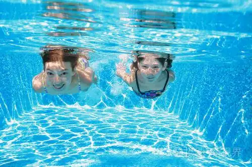 快乐积极的女孩玩水,孩子们健身和运动活跃家庭度假的游泳池里游泳