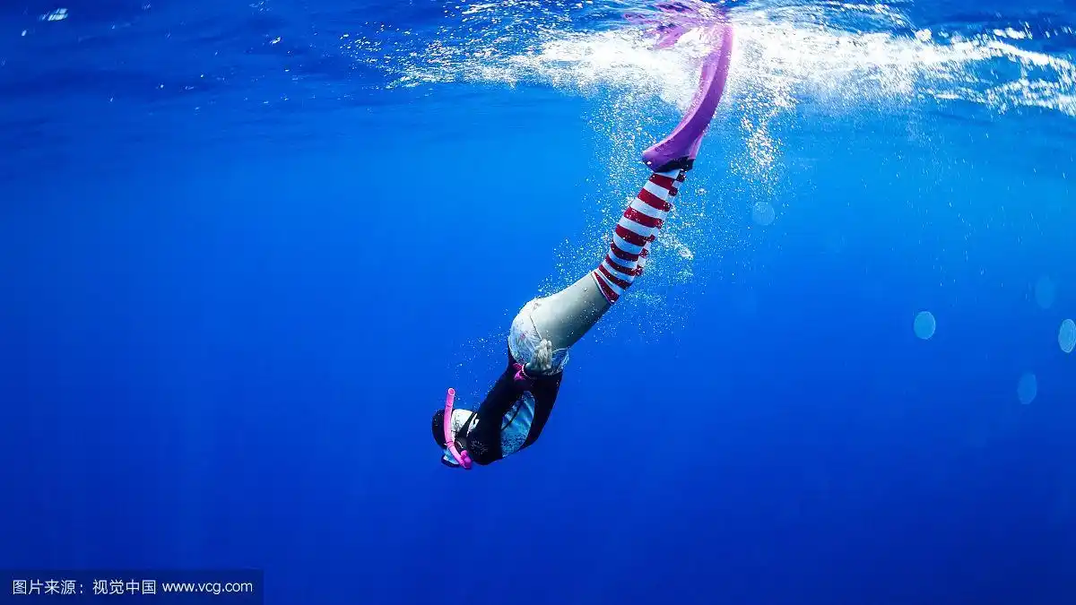 穿着红色条纹袜带着粉红色呼吸管的自由女性潜水员