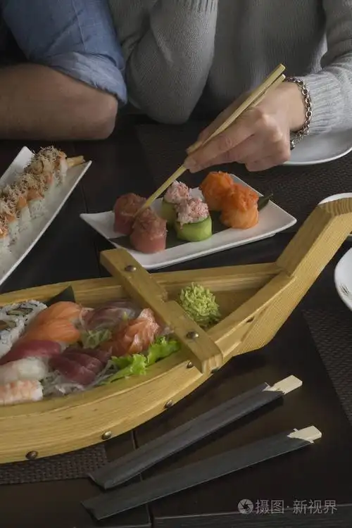 高加索年轻夫妇吃寿司木船在餐厅关闭视图