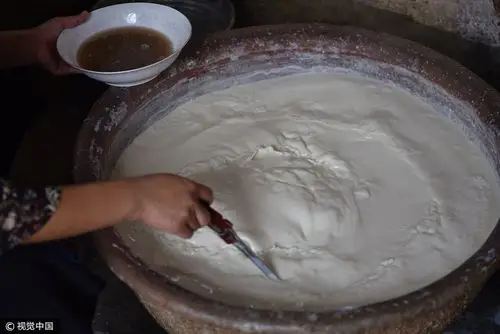 李秀玲正在用卤水点豆腐.  图片来源:刘明照/视觉中国