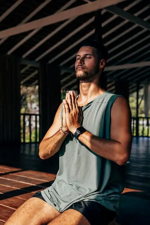 男子坐在疗养胜地,双手合十冥想图片下载