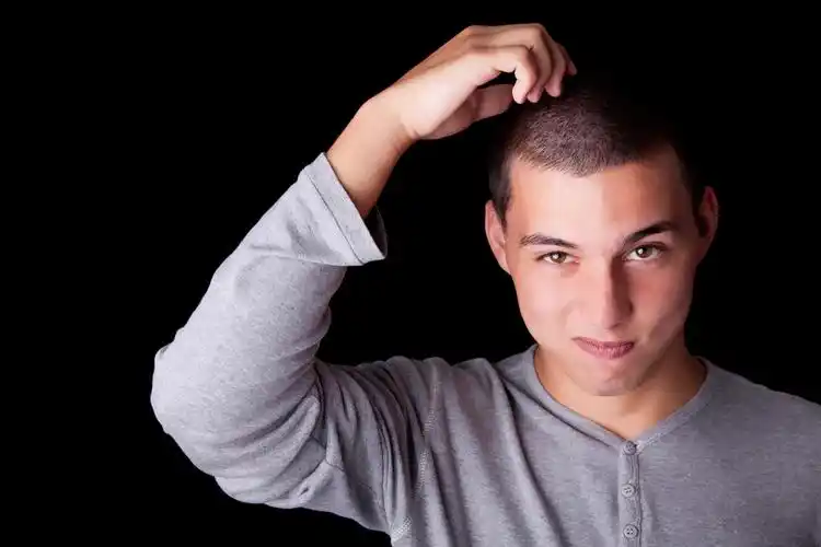 抓头,年轻人,抓他的头.工作室拍摄在黑色的背景上.