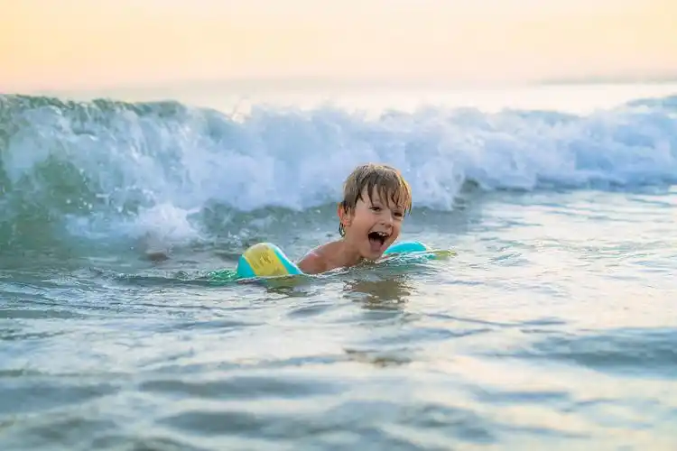 孩子在海里玩得很开心,在日落的海滩上游泳和玩海浪.