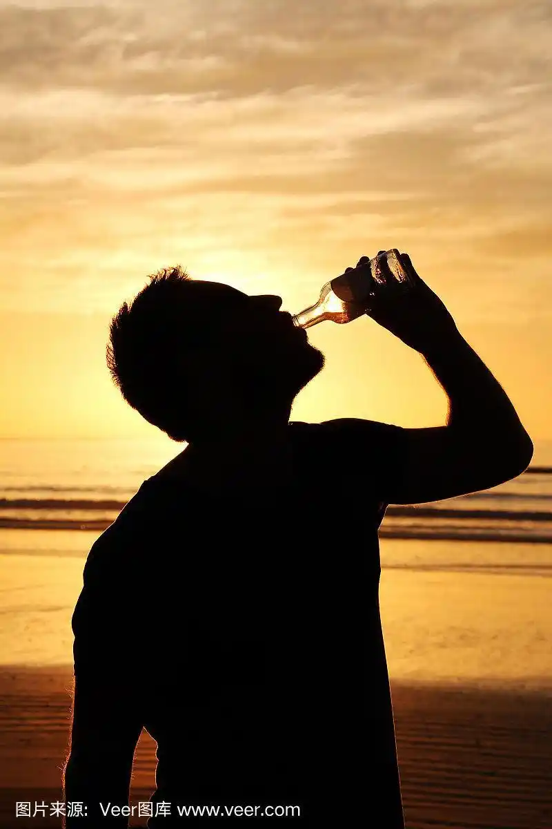 在非洲日落时喝啤酒的男人