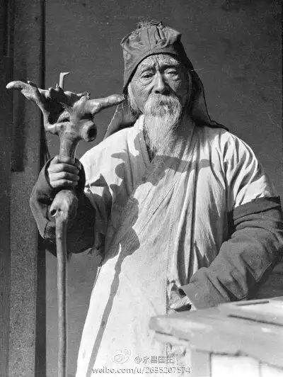 民国初期,浙江杭州地区的一位老算命先生,手中持仗,头戴风帽身穿交领