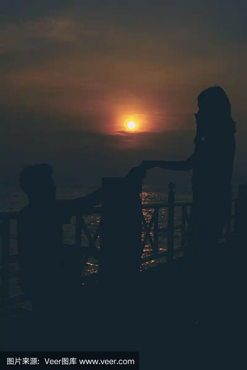 日落时分,一对情侣在海边拥抱的剪影.