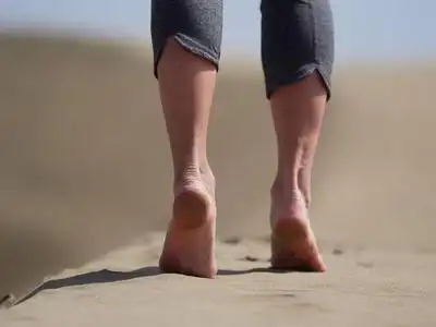 日出时,年轻女子赤脚在海滩上慢跑散步照片