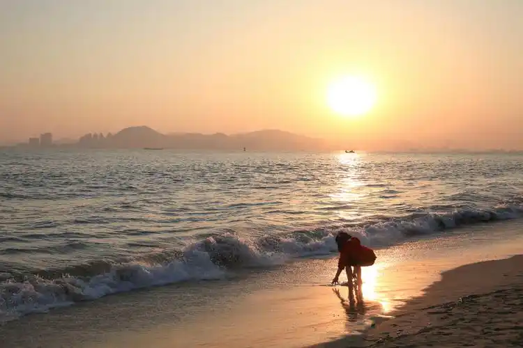 厦大白城沙滩,落日余晖下,小女孩儿在海边嬉戏.
