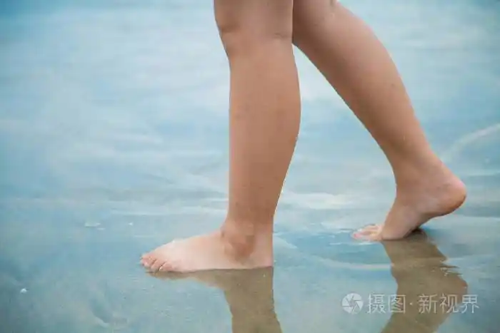 白天女人的脚在沙滩上行走去争取
