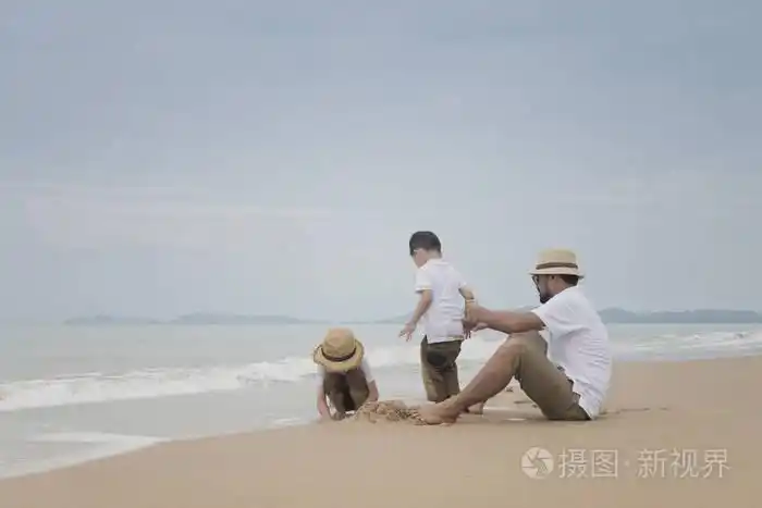 亚洲父亲在阴沉的日子里和儿子一起在沙滩上玩耍