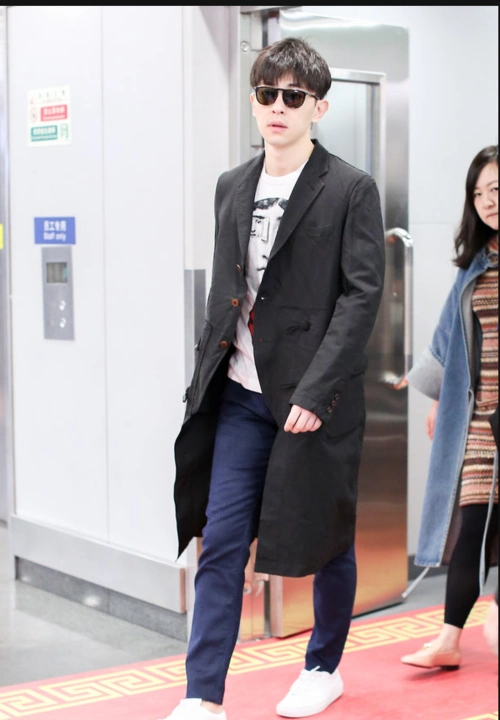邓伦穿黑色风衣现身机场 拎黑色大包包简约有型