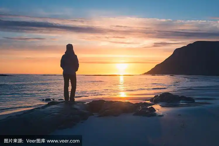 一个人的剪影在日落的海边和岩石