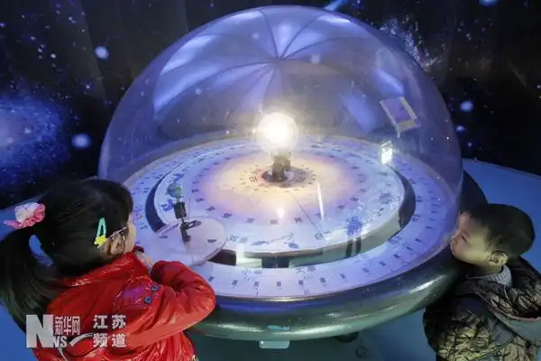 两名小朋友在南京科技馆内参观模拟演示太阳,地球和月亮三者之间