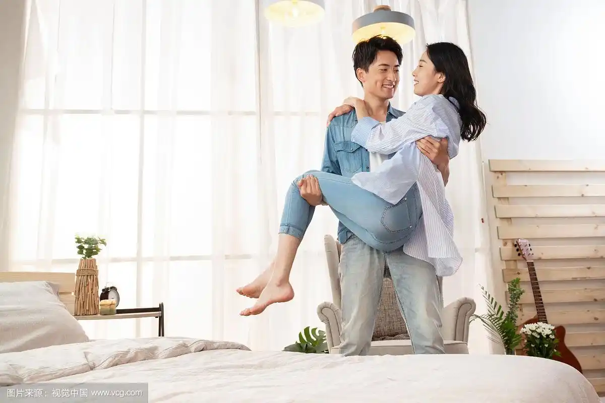 卧室里年轻丈夫把妻子抱了起来