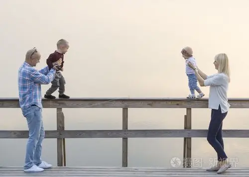 幸福的家庭,两个父母和孩子,一个男孩子,女婴,在河码头上有好的时间.