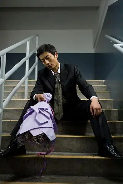 坐在建筑台阶上手捧鲜花等人的男士