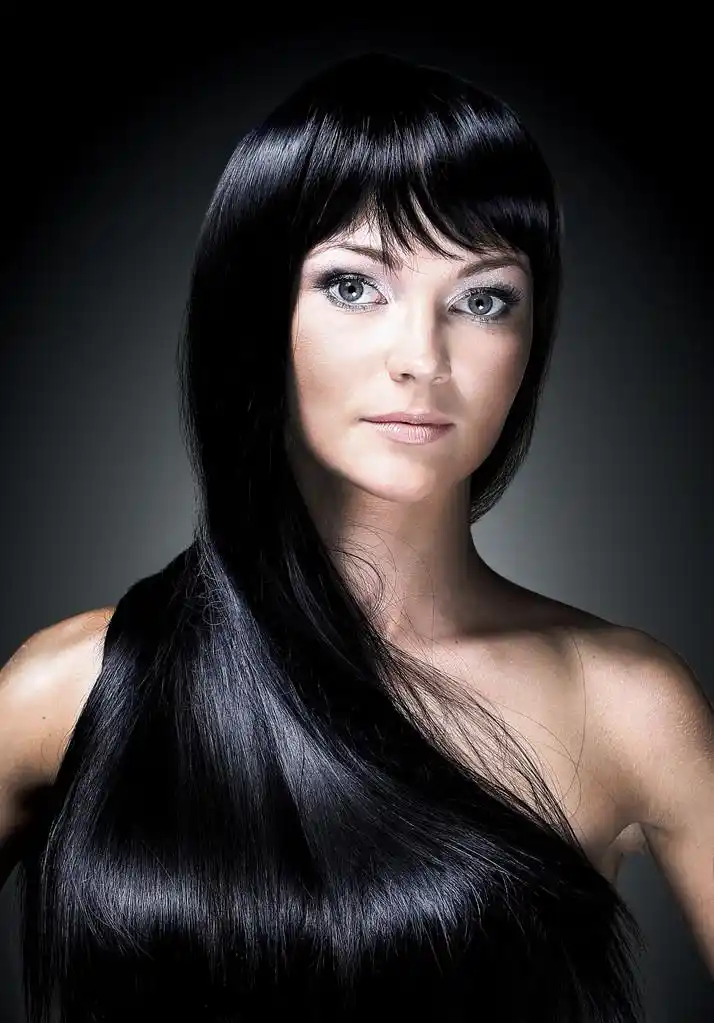 一个美丽的年轻女子,与长闪亮的秀发的画像.黑色背景上孤立