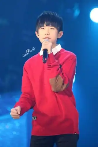 图片中的易烊千玺穿着一件红色毛衣在台上唱歌,简直帅呆了.