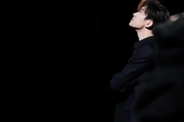 易烊千玺工作花絮穿黑西服站灯光下侧颜帅气