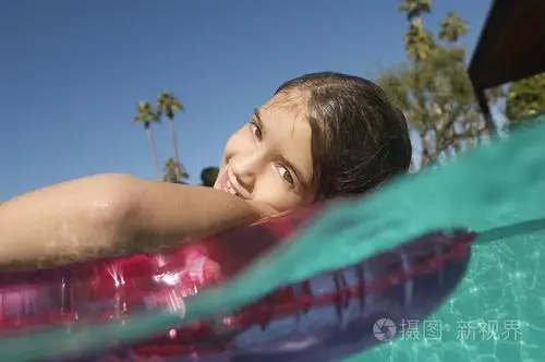 可爱的女孩在游泳池中漂浮
