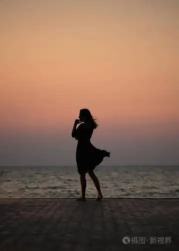 一个女孩在日落背景(日出)上的剪影在海平线上. 夏天在海滩上散步.