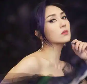 舞台上的杨千嬅身穿带有花朵的深紫色抹胸长裙,发型和指甲的颜色也都