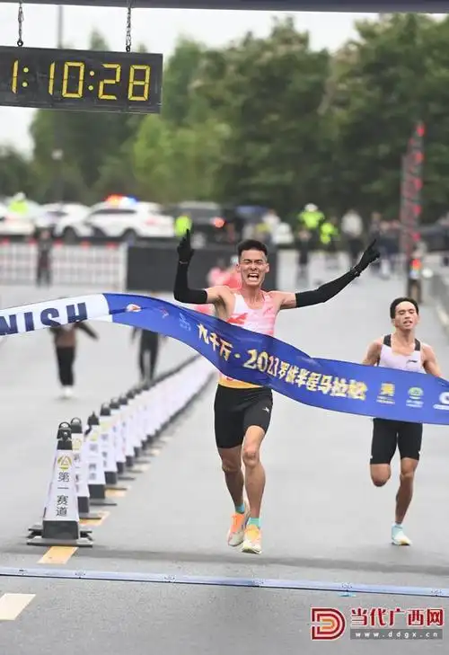 在广西罗城仫佬族自治县城东工业园区,半程马拉松赛选手冲过终点