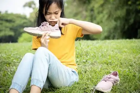 很臭亚洲女青少年闻着她的运动鞋,手里拿着臭鞋,难闻的气味,炎热的