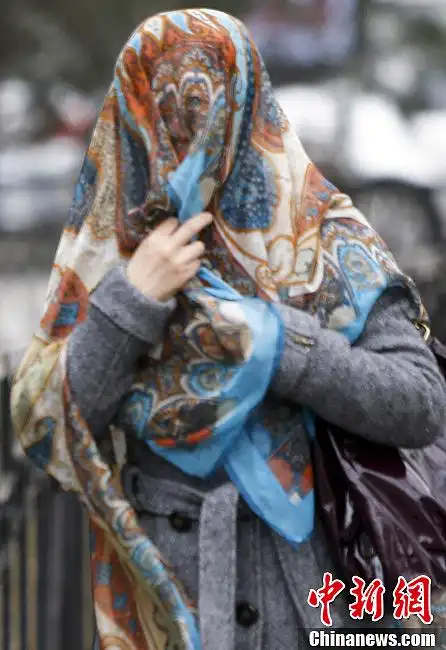 3月9日,一名女士裹着纱巾在北京街头行走,当日北京遭遇今春第二次大风