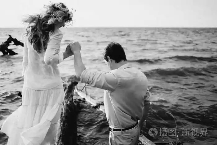 黑白照片一对相爱的幸福夫妇,他们在日落时分在海滨共度时光