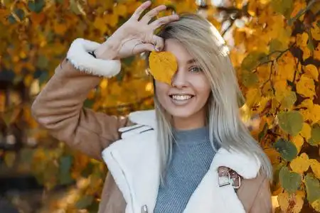 微笑金大衣一个快乐美丽的年轻女子的肖像,在阳光明媚的日子里,在秋天