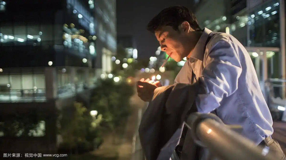 商人晚上倚在桥栏杆上抽烟的照片