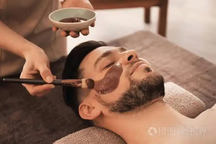 美容美发师在水疗沙龙男士脸上涂抹面膜