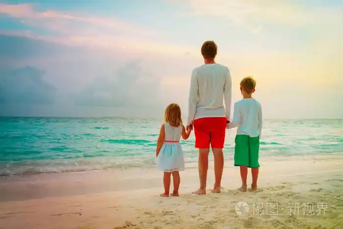 父亲与儿子和女儿牵手在日落海滩