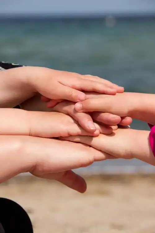 阳光下将手重叠在一起的一家人