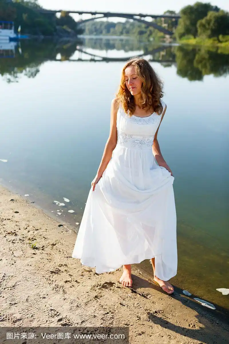 年轻快乐的少女新娘赤脚走在河边