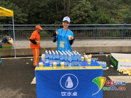 图为5公里补给站志愿者为半程马拉松参赛者准备饮水.