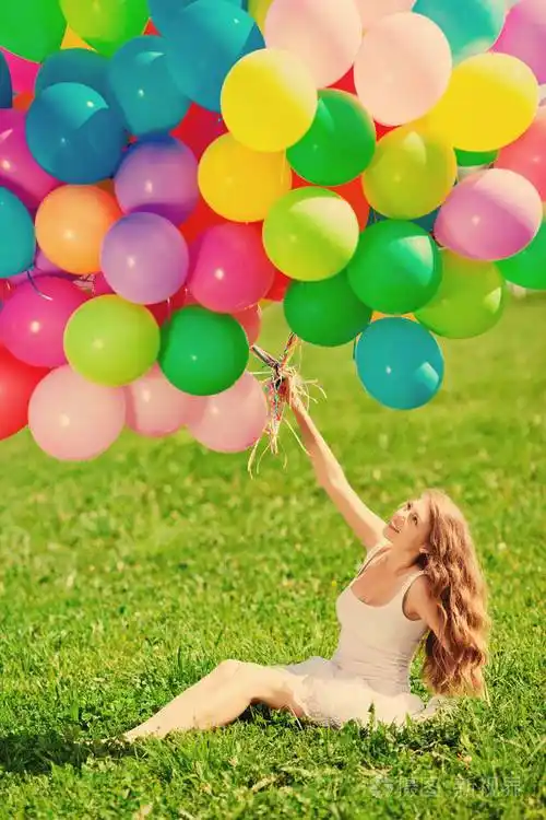 生日快乐的女人靠在天空上,手里拿着彩虹色的气球.