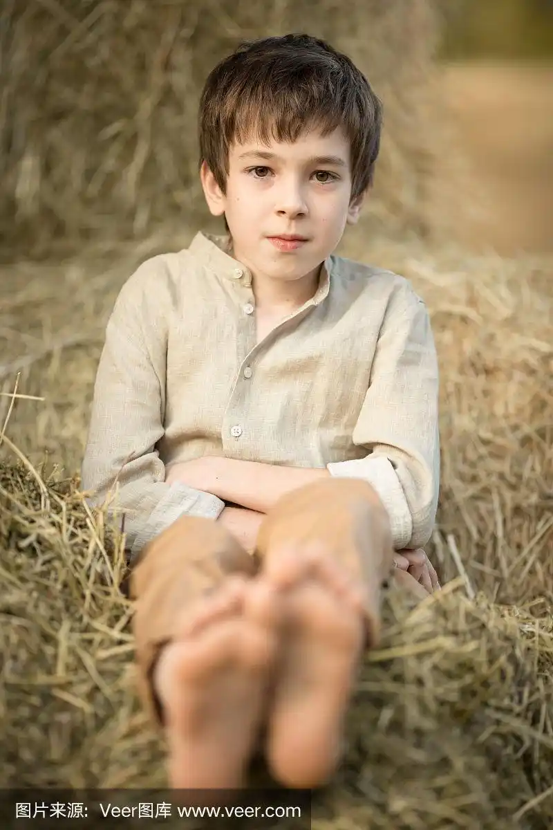 赤脚乡村男孩休息休息,躺在干草上.