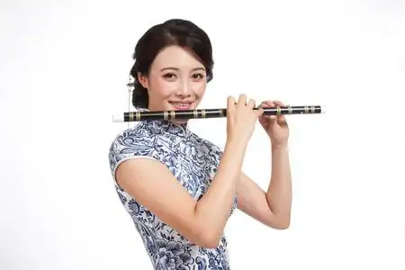 棚拍身穿旗袍的年轻女人吹笛子照片