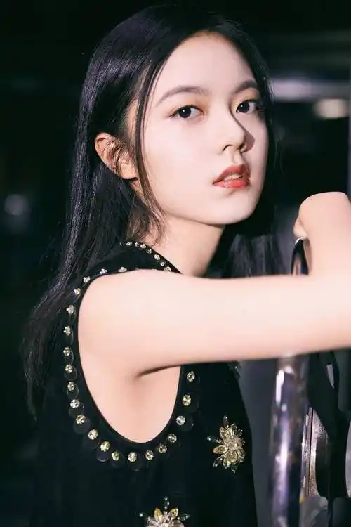 赵今麦身穿黑白条纹无袖上衣,搭配白色短裙和黑靴子,她单手托着俏脸