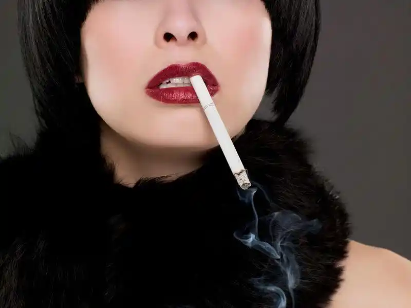 黑色背景中熏烟从美女嘴里冒出来