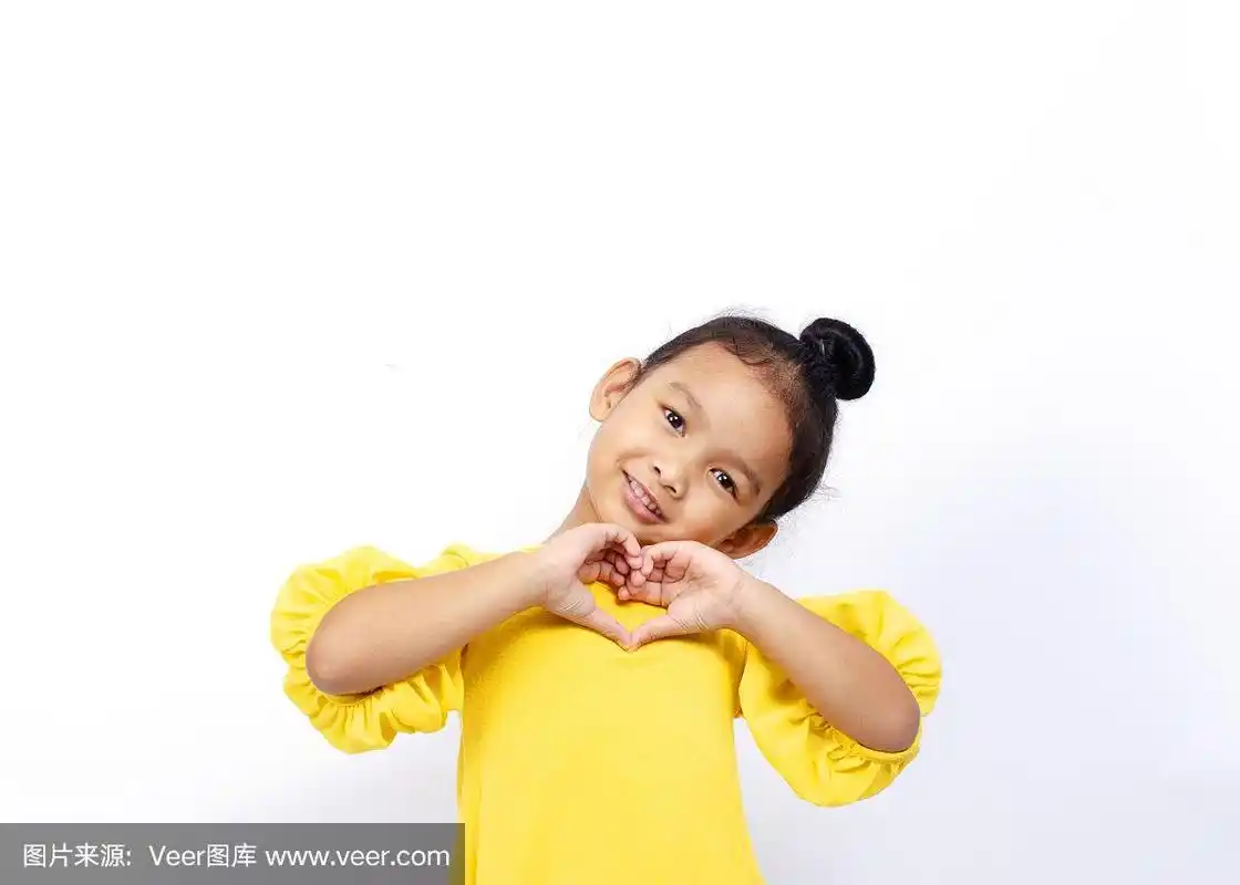 可爱的亚洲婴儿女孩孩子肖像微笑和显示心形手势在白色的背景