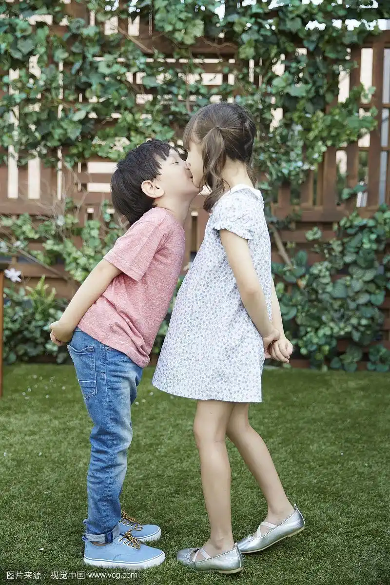 幼儿园男孩和女孩站着接吻的照片