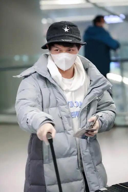 周深温暖走机场,穿羽绒服卫衣配渔夫帽,眼角褶皱堆积却意外很帅